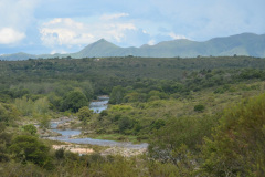 Imagen del Yuspe, el principal afluente del río Cosquín, a poco de superar el azud de toma de agua. Al fondo, la silueta del cerro Pan de Azúcar.