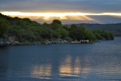 Desde uno de los cierres laterales de la presa Cerro Pelado, se observa una puesta de Sol entre las nubes.