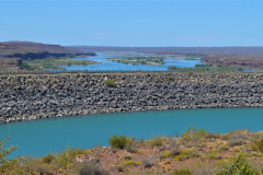 En la imagen se puede ver en primer plano una parte del lago, en segundo plano la represa, y al fondo el río Limay tal como emerge de la misma.