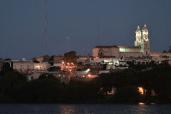 Desde la costa de Viedma, al anochecer puede observarse el perfil iluminado de la Catedral y otros edificaciones de Carmen de Patagones.